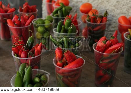 Many Plastic Cups With Fresh Chilli Peppers On Grey Counter At Market, Closeup