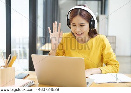 Young Asian Female Student Studying Online Using Laptop And Holding Mobile Phone Surfing The Interne