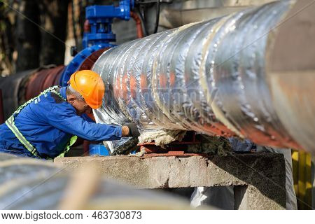 Bucharest, Romania - October 13, 2022: Worker Uses Glass Wool To Thermal Insulate A Hot Water Metall