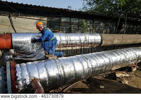 Bucharest, Romania - October 13, 2022: Worker Uses Glass Wool To Thermal Insulate A Hot Water Metall