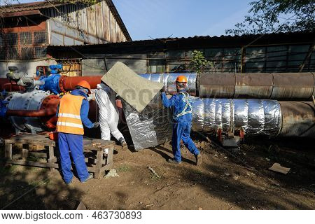 Bucharest, Romania - October 13, 2022: Worker Uses Glass Wool To Thermal Insulate A Hot Water Metall