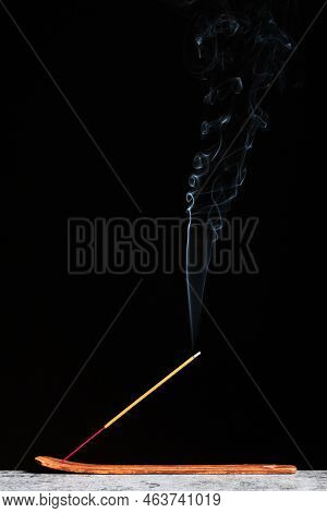 Burning Incense Stick Stands On A Wooden Stand Isolated On A Black Background