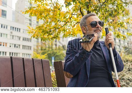 Elegant Blind Bearded Grey-haired Mature Man With Dark Sunglasses On Holding A Walking Stick, Enjoyi