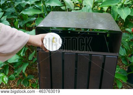 Women Hand Throwing An Empty Plastic Water Bottle In The Garbage Trash Or Bin