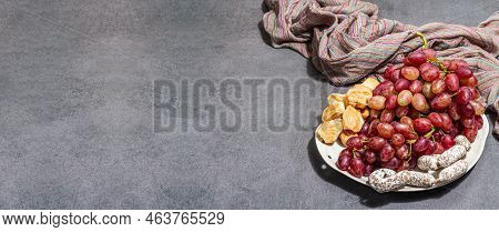 Snack Plate With Cheese, Grapes And Dried Sausages. Charcuterie Antipasto, Stone Concrete Background