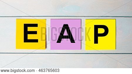 Three Multi-colored Paper Stickers With Eap Employee Assistance Program Text On A Blue Wooden Backgr