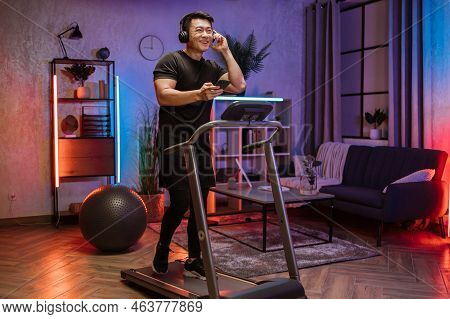 Pozitive Asian Men In Sports Clothes And Sneakers Listening Music In Headphones While Using Smartpho