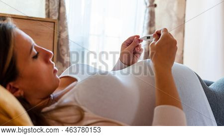 Pregnant Temperature Fever Check. Pregnancy Woman Holding Thermometer, Check Fever Flu Temperature. 