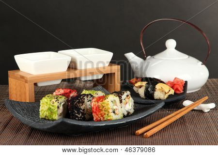 Velsmagende Maki sushi - Roll på grønne blade på bordet på grå baggrund