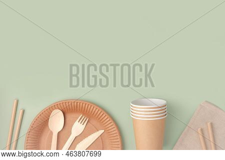 Eco - Friendly Tableware On Green Background. Top View. Plastic Free Set Of Brown Paper Utensil. Str
