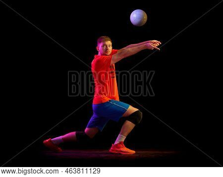 Dynamic Portrait Of Male Volleyball Player Training With Ball Isolated On Dark Background In Neon Li