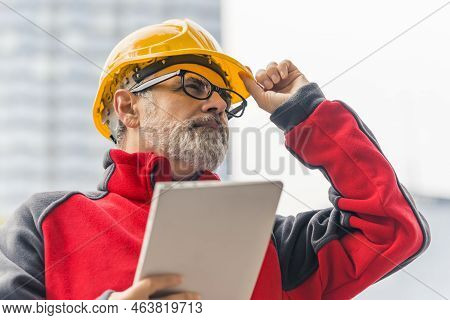 Experienced Professional Architect Compering Ongoing Works With His Project Placed On Portable Table