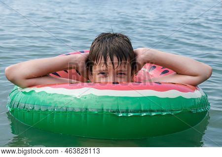 A Young Playful Happy Teenage Boy Relaxing On An Inflatable Ring , Floaty In The Sea During Summer V