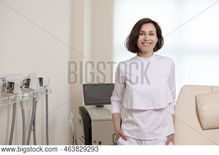 Business Portraits. Confident Female Doctor Posing In Doctor's Smock With Hands Folded In Front Agai