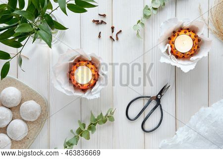 Wintertime Table With Fragrant Candles Made Of Orange And Cloves. Ceramic Board With Gingerbread Coo