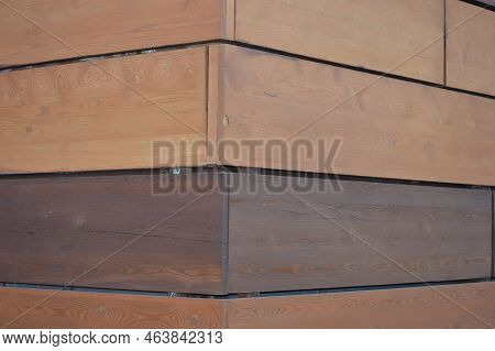 Facing The Facade Of The Building With Decorative Brown Wood Panels. Corner Of The House. Geometric 