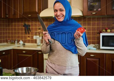 Charming Arabic Muslim Woman Housewife In Blue Hijab, Smiling A Toothy Smile, Looking At Camera, Sta
