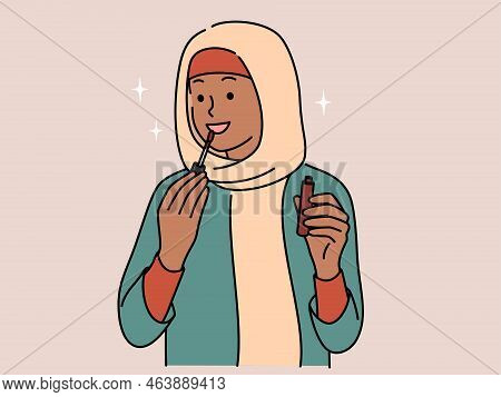 Smiling Young Arabic Woman In Hijab Applying Lip Gloss On Lips. Happy Arabian Girl Do Makeup. Beauty