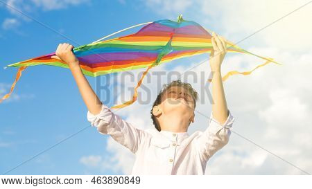 A Boy 8-9 Years Old Happily Launches A Kite Into The Sky.
