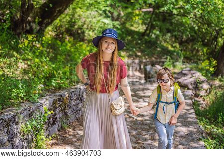 Mother And Son Tourists Climb The Mountain To The Ostrog Temple. Monastery Of Ostrog, Serbian Orthod
