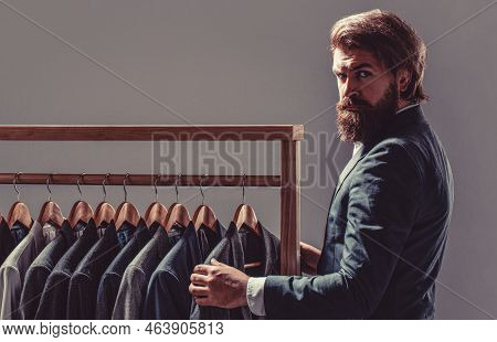 Elegant Mans Suits Hanging In A Row. Luxury Mens Classic Suits On Rack In Elegant Mens Boutique