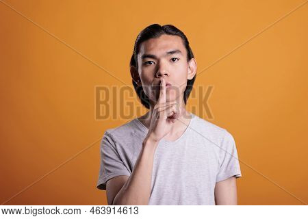 Young Adult Asian Man Showing Quiet Gesture, Making Tsss Sign, Silence Concept. Confident Teenager L