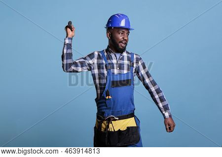 African American Construction Worker Wearing Coverall And Tool Belt Annoyingly Throwing Hammer. Stre
