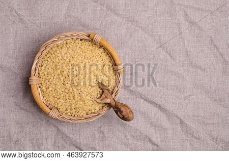 Traditional Dry Pearl Couscous In A Wicker Basket On A Textile Background. Top View.