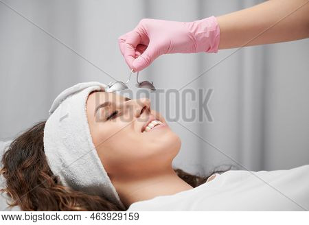 Close Up Of Womans Face Who Lying With Closed Eyes At Reception At Beautician. Cropped View Of Hand 