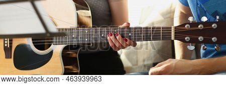 Close-up Of Female Teacher Explain Notes To Client On Guitar Instrument, Music Class At Home. Female
