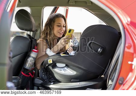 Mother Taking A Picture Of Her Son In The Car Seat