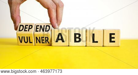 Vulnerable Or Dependable Symbol. Businessman Turns Wooden Cubes And Changes The Word Vulnerable To D