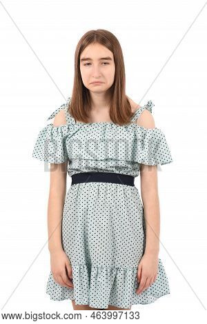 Young Beautiful Girl In A Blue Dress With Polka Dots On A White Background, Sad Expression Like A Sm