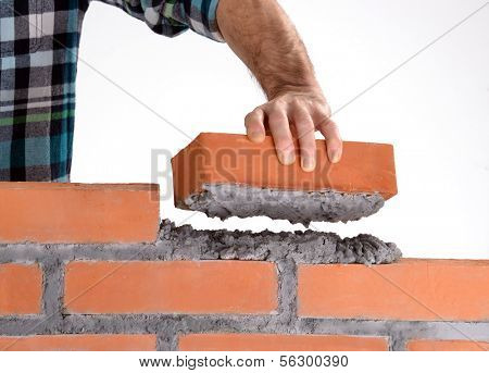Constructor hand holding a brick and building a wall.