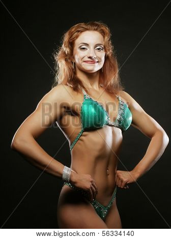 A beautiful woman bodybuilder posing in green  bikini