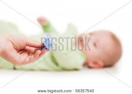 Mother hand giving plastic soother pacifier to little cute sleeping newborn baby child white isolated