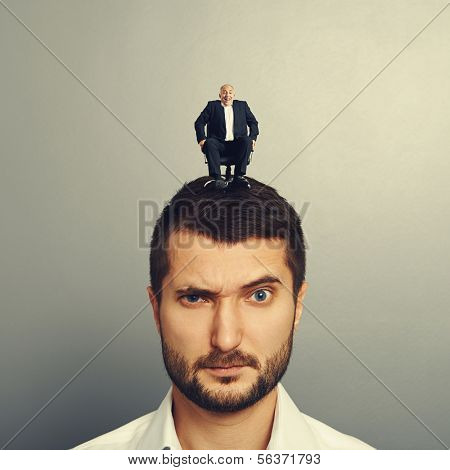 portrait of dissatisfied man with small man on the head