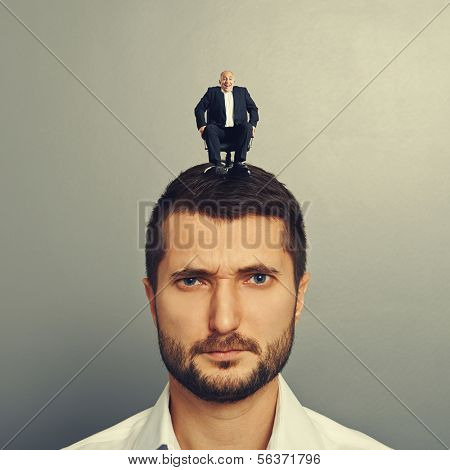 portrait of sad man with small man on the head