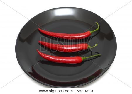 Tree röd chilipeppar på en tallrik