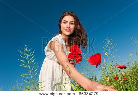 Summer girl in poppy field holding a poppies bouque