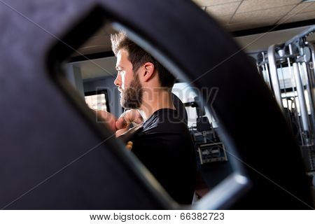 Barbell man weightlifting workout view through a weight bell hole