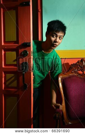 Young asian teen peeking and sneaking in into a living room