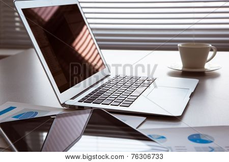 The workplace of business people. Laptop, raphs, charts, business table.