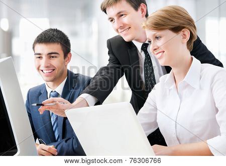 Young business people sitting at desk, using computer at business training, smiling.
