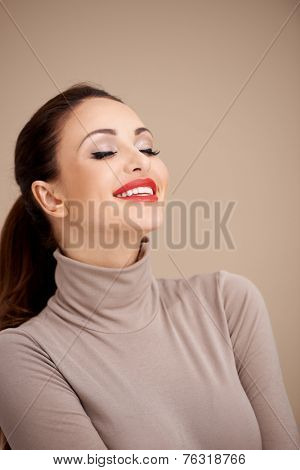 Close up Pretty Smiling Woman Wearing Closed Neck Gray Fashion Attire Doing Daydreaming with Closed Eyes. Isolated on Brown Background.