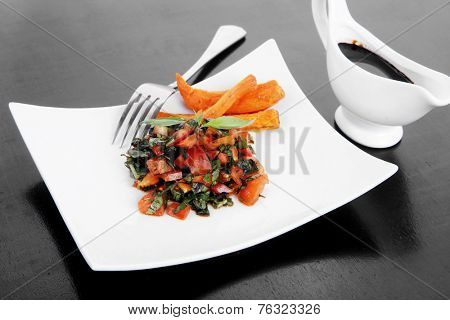 vegetable salad : cherry tomatoes and basil with sweet baked potato served on white plate with sauceboat full blask soy sauce on wood
