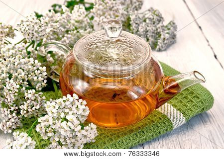 Tea with yarrow in glass teapot on napkin