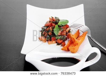 vegetable salad : cherry tomatoes and basil with sweet baked potato served on white plate with sauceboat full blask soy sauce on wood
