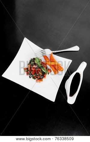 vegetable salad : cherry tomatoes and basil with sweet baked potato served on white plate with sauce boat full blask soy sauce on wood