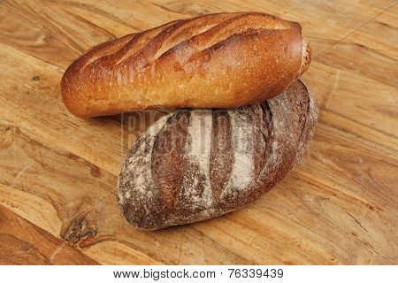 different rye and white flour french bread loaf with on light wooden table background